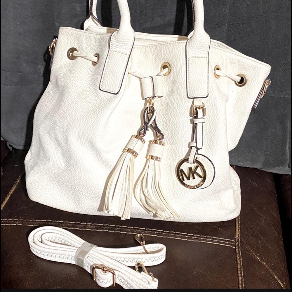 White purse, with shoulder strap, has handles
